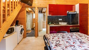 Ein kompakter Raum mit Bett, Waschmaschine, Mikrowelle, Spüle und einer kleinen Küchenzeile.