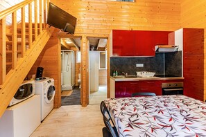 Ein kompakter Raum mit Bett, Waschmaschine, Mikrowelle, Spüle und einer kleinen Küchenzeile.
