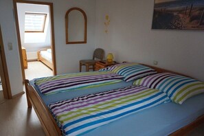 A bedroom with a bed, a chair, a lamp, and a painting on the wall. - Holiday home in Cuxhaven with swimming pool (Cuxhaven)
