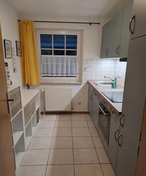 A compact kitchen with a window, white cabinets, a radiator, and a sink. - Holiday home in Cuxhaven with swimming pool (Cuxhaven)