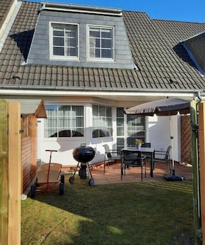A house with a covered patio, a barbecue grill, and a table with chairs. - Holiday home in Cuxhaven with swimming pool (Cuxhaven)