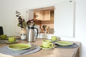 Ein Essbereich mit einem Tisch für vier Personen, einer Kaffeekanne und einer Blumenvase.