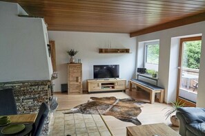 Ein Wohnzimmer mit Kamin, Fernseher, einer hölzernen Bank und einem großen Teppich.