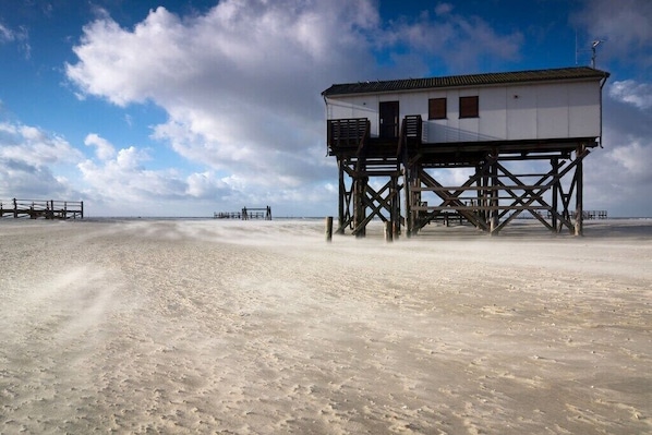 Ein Strandhaus mit Balkon, Treppe und Blick auf den Strand.