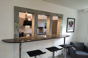 Uma cozinha moderna com bancada de mármore, um relógio e um quadro pendurado na parede.