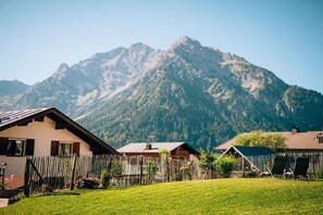 Ein Berggrundstück mit Holzzaun, einer Rasenfläche und Blick auf die Berge.