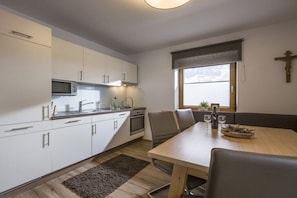 Eine moderne Küche mit weißen Schränken, einer eingebauten Mikrowelle und einem Essbereich mit Tisch und Stühlen.