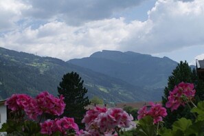 Eine Berglandschaft mit einem Haus im Vordergrund und wolkenlosem Himmel.