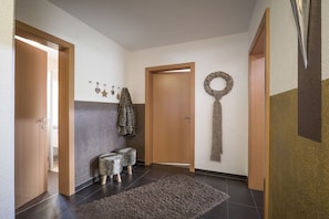 Ein Flur mit Holztür, einer Bank, einem Teppich und Wandverzierungen.