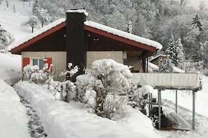 A snow-covered house with a red roof, a chimney, and a small porch. - Holiday home in Vitznau with swimming pool (Vitznau)
