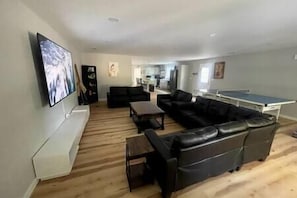 Una sala de estar con sofá, mesa de centro, televisor y mesa de ping pong.
