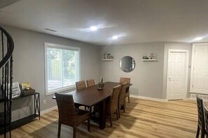 Un comedor con una mesa y sillas, una ventana con persianas, un espejo y una puerta.
