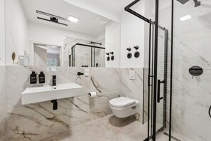 A modern bathroom with a glass shower enclosure, a white sink, and a marble floor. - Residence Hugo - Penthouse Apartment (Bad Schandau)