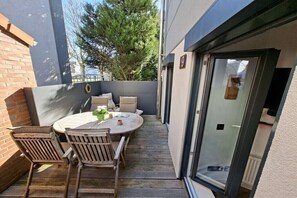 A patio with a round table and chairs, a small garden area, and a sliding glass door. - Black-headed Seagull by DeJu Norderney (4**** DTV) (Norderney)