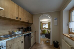 Eine kleine Küche mit Holzausstattung, einem Geschirrspüler und einem Essbereich mit Tisch und Stühlen.