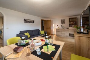 Ein modernes Wohnzimmer mit Sofa, Esstisch und Küchenzeile.