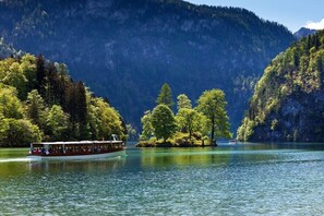 Ein Boot auf einem stillen See, umgeben von bewaldeten Hügeln.