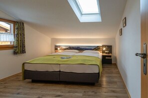 Ein Schlafzimmer mit Dachfenster, einem Bett, einem Nachttisch und einer Wandlampe.