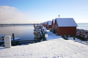 A row of red buildings with a dock extending into calm water. - Large Baltic Sea nest (Boltenhagen)