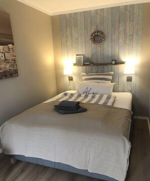 A bedroom with a bed, two bedside lamps, a wall clock, and a decorative wreath. - Large Baltic Sea nest (Boltenhagen)
