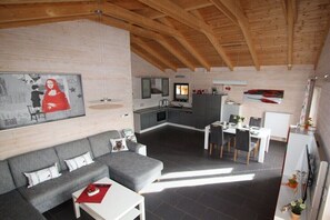Ein modernes Interieur mit Essbereich, Küche und einem grauen Sofa mit rotem Tisch.