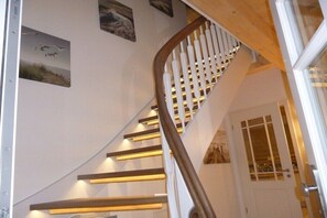A spiral staircase with wooden steps and a white railing, leading to a door with glass panels.