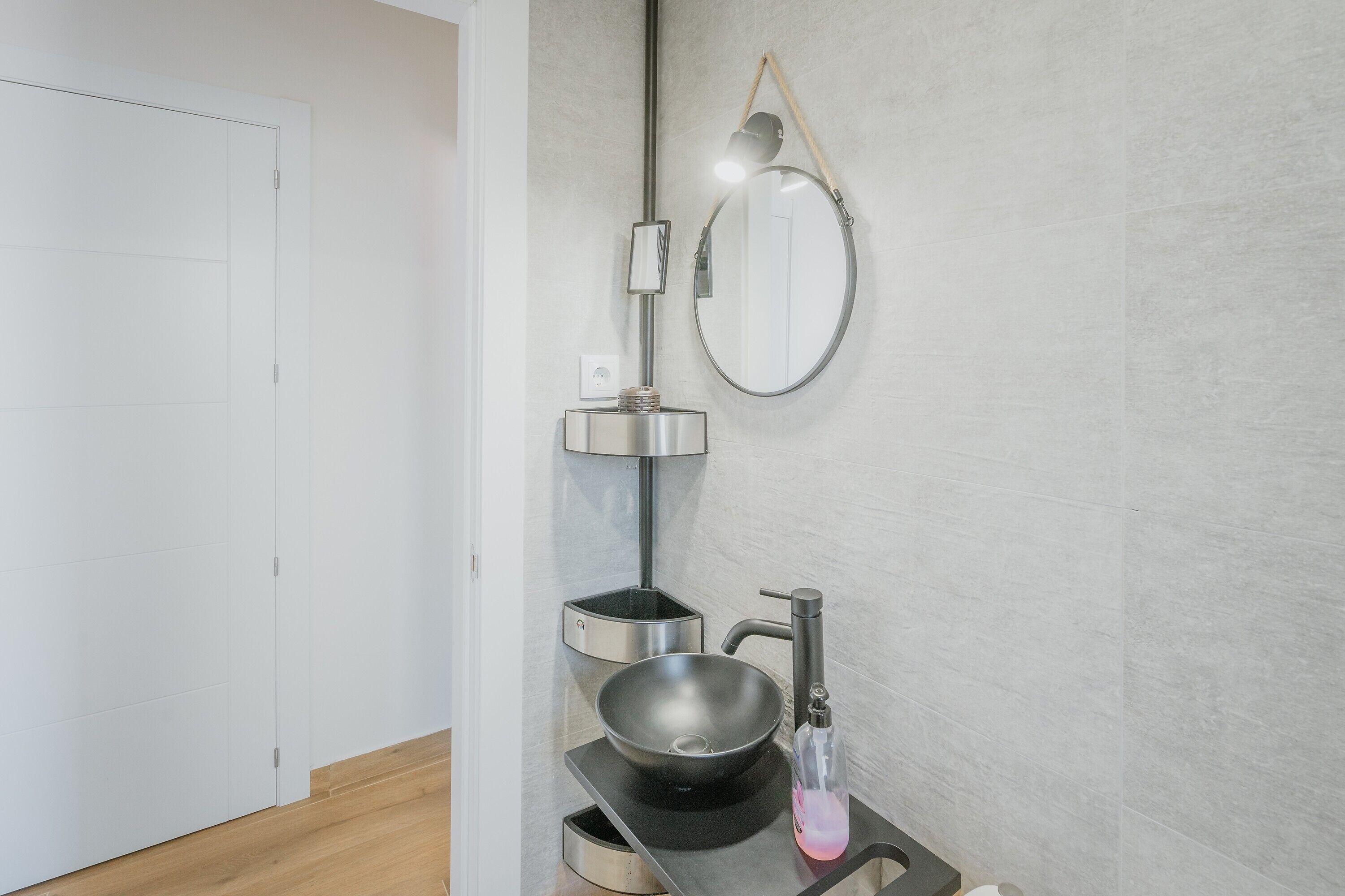 Un bagno moderno con un lavandino nero, uno specchio e un porta asciugamani.