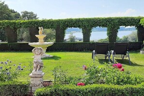 A garden with a fountain, chairs, and a view of a lake. - Holiday home with lake view (Driedorf)