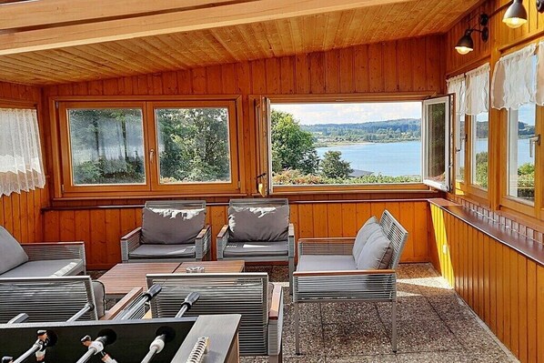 A wooden cabin with a view of a lake, furnished with chairs and a table. - Holiday home with lake view (Driedorf)