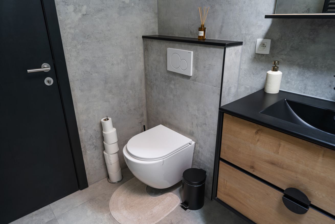 Un baño moderno con inodoro, lavamanos y armario de almacenamiento.