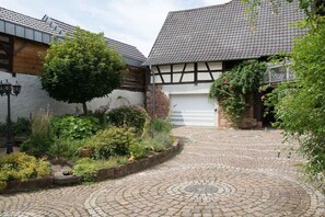 Un patio con senderos adoquinados, un árbol y un edificio con puerta de garaje.