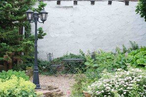 Un jardín con un farol, una mesa y diferentes plantas.