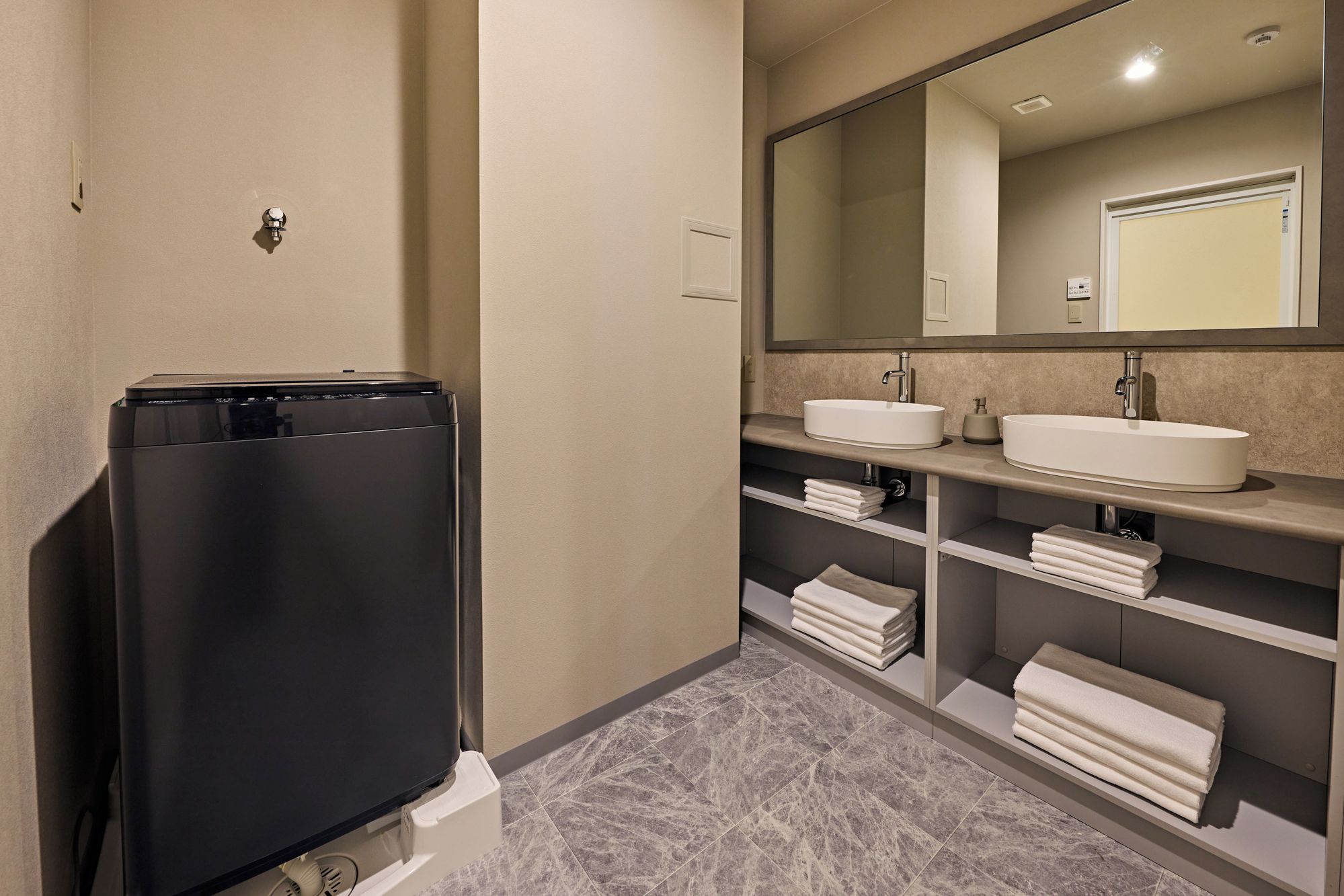 A modern bathroom with a black appliance, two sinks, and a large mirror.