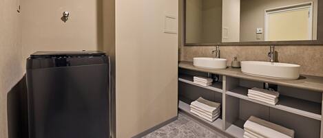 A modern bathroom with a black appliance, two sinks, and a large mirror.