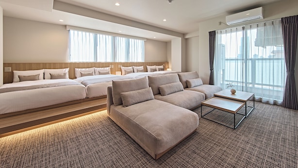 Ett hotellrum med en stor säng, en soffa, ett soffbord och utsikt över staden genom fönstren.