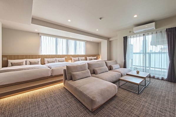 A hotel room with a large bed, a sofa, a coffee table, and a view of the city through the windows. - NICO HOTEL Osaka Namba (Osaka)