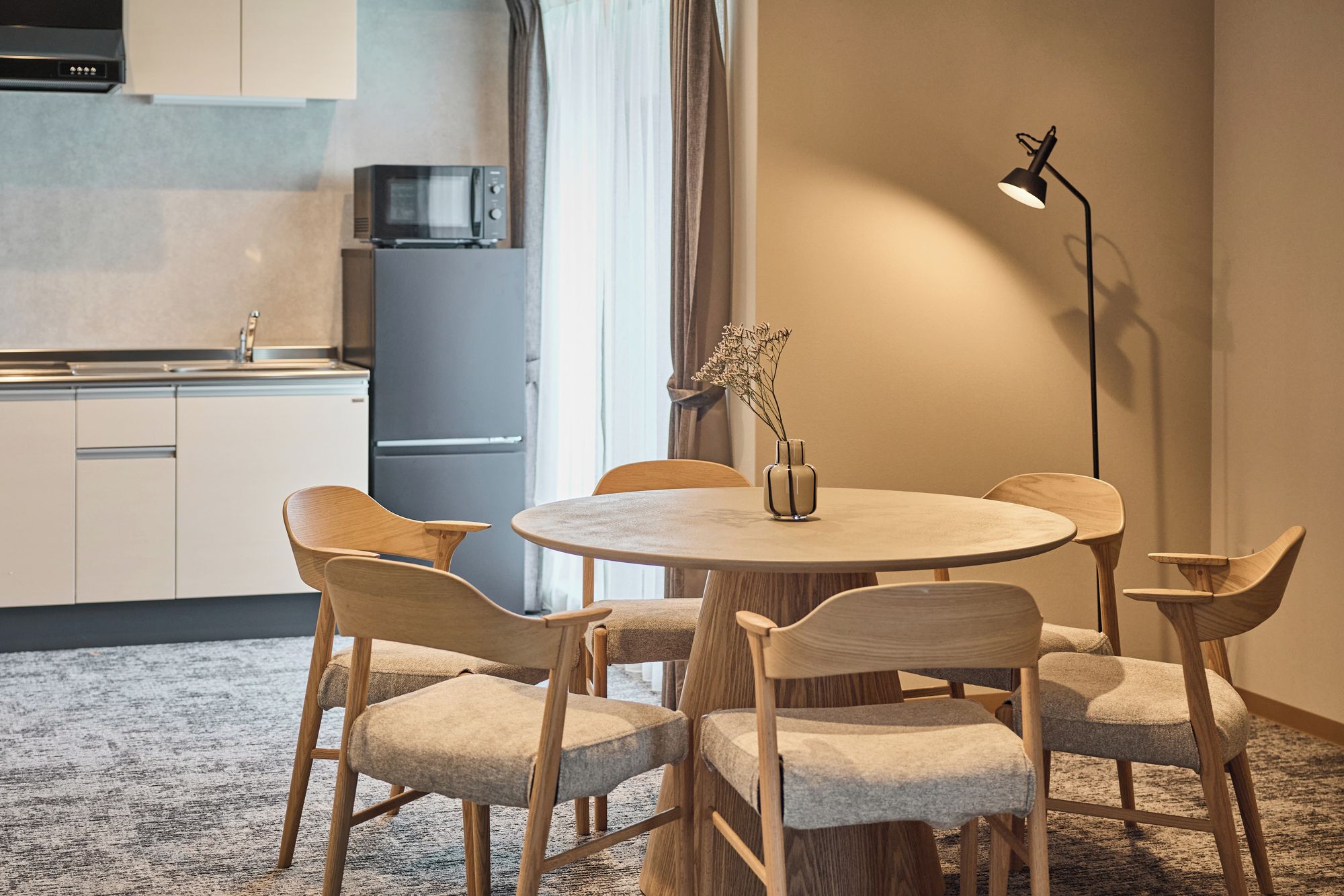 Eine moderne Küche mit Mikrowelle, Kühlschrank und Essbereich mit rundem Tisch und vier Stühlen.