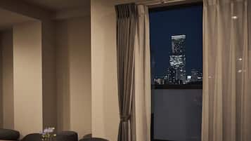 A modern hotel room with a large window overlooking a cityscape at night.