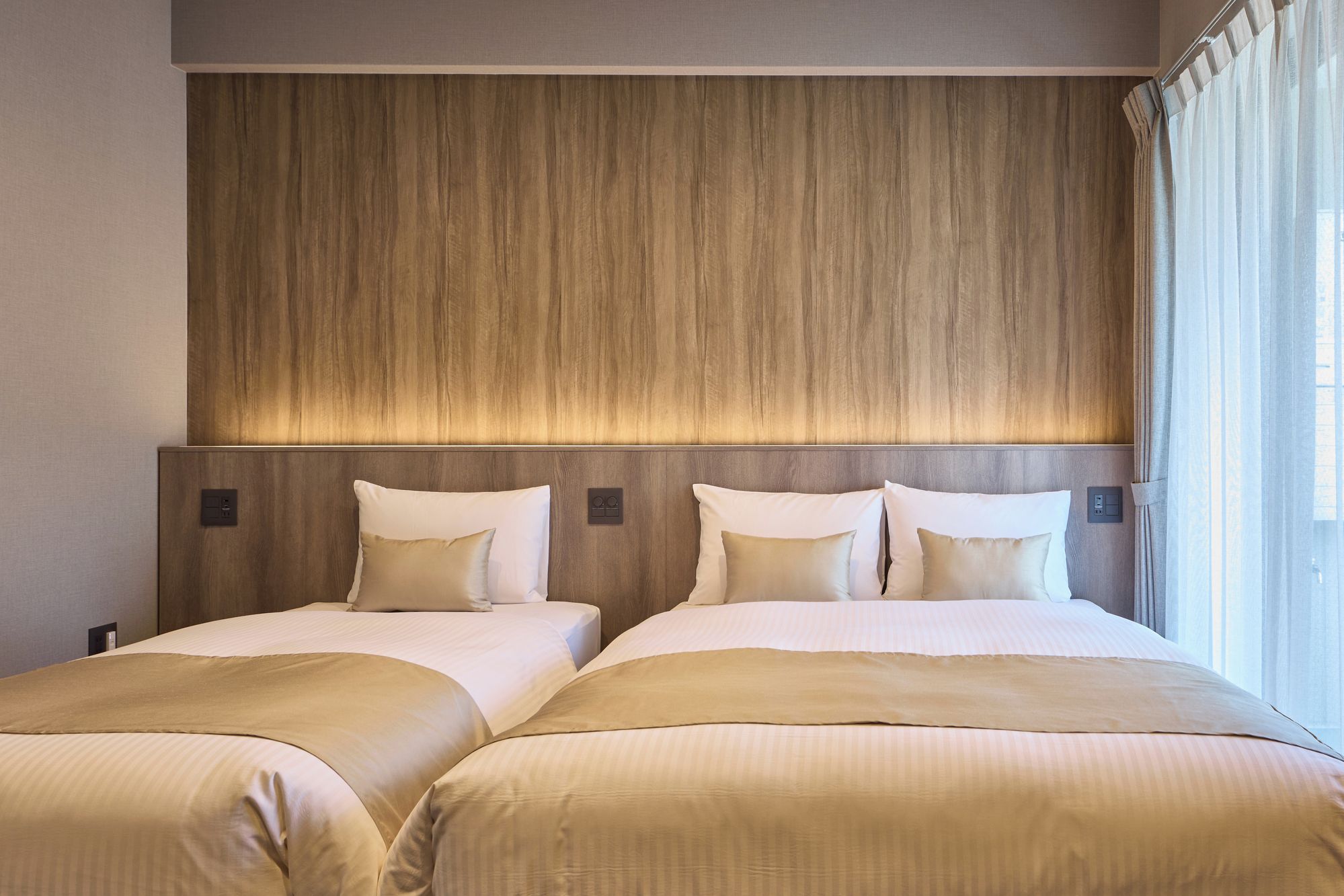 A hotel room with two beds, a wooden headboard, and a window with curtains.