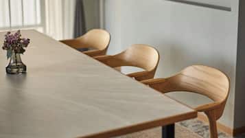 A conference table with chairs, a vase with flowers, and a window with blinds.