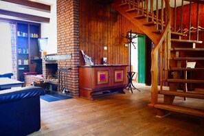 A wooden staircase, a brick fireplace, and a bookshelf in a room with wooden flooring. - Holiday home in Essel with swimming pool (Essel)