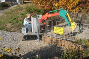 A construction site with a metal fence, a small excavator, and a warning sign in German. - Holiday home with 3 bedrooms (Frielendorf)