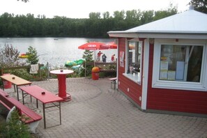 A lakeside restaurant with outdoor seating, a red building, and a view of the lake. - Holiday home with 3 bedrooms (Frielendorf)