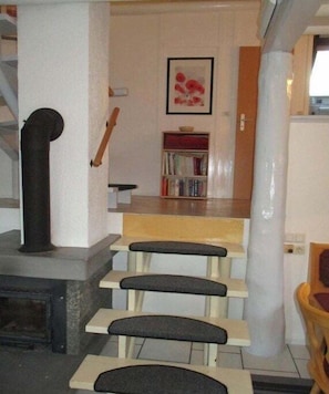 A staircase leading to a kitchen area with a bookshelf and a framed picture on the wall. - Holiday home with 3 bedrooms (Frielendorf)