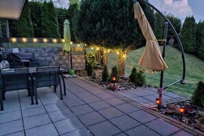 Eine Terrasse im Freien mit Grill, Stühlen und Lichterkette.