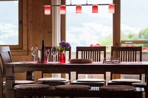 Ein Holztisch mit Stühlen, einer Blumenvase und einer Flasche.
