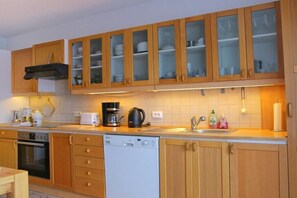 Eine Küche mit Holzausstattung, einem Geschirrspüler, einem Backofen, einer Kaffeemaschine und einem Waschbecken mit Seifenspendern.