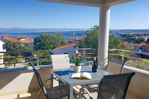 Ein Balkon mit Tisch, Stühlen, einer Topfpflanze und einem offenen Buch.
