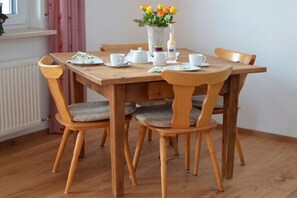 Ein Holzespeisetisch mit sechs Stühlen, einer Blumenvase und einer Weinflasche.