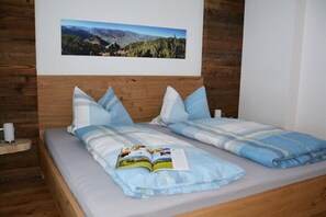Ein Doppelbett mit einer blau-weiß gestreiften Bettdecke, Kissen und einem Buch darauf.